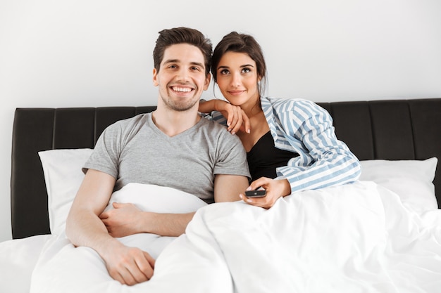 Retrato de una joven pareja feliz sentados juntos en la cama
