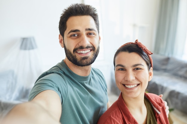 Retrato de joven pareja feliz sonriendo, haciendo retrato selfie en casa