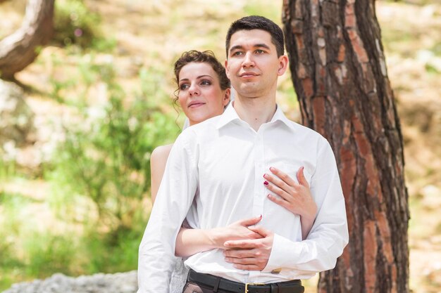 Foto retrato de una joven pareja de pie contra el tronco de un árbol