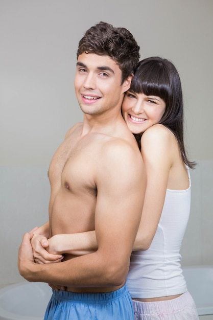 Retrato de joven pareja sonriendo y abrazados unos a otros en el baño.