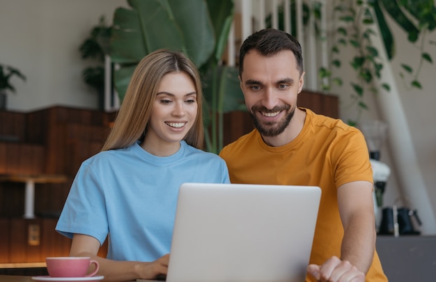 Retrato de joven pareja sonriente con ordenador portátil, internet, comunicación