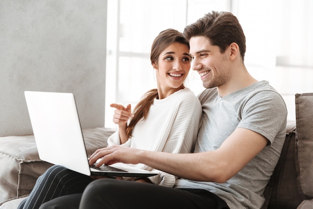 Retrato de una joven pareja sonriente con ordenador portátil