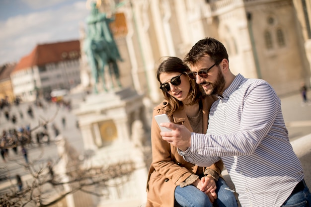 Retrato de la joven pareja de turistas en la ciudad mediante teléfono móvil