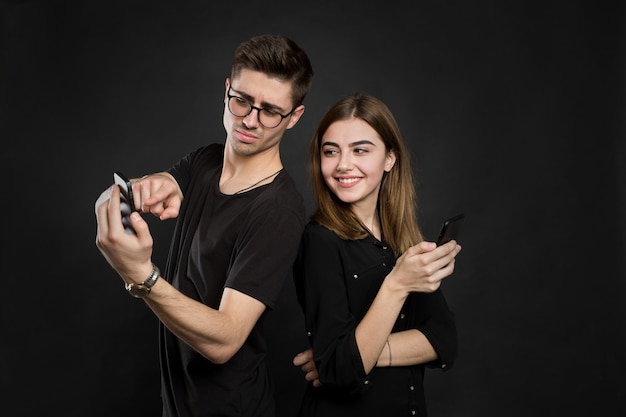 Retrato de una joven pareja viendo información en sus teléfonos