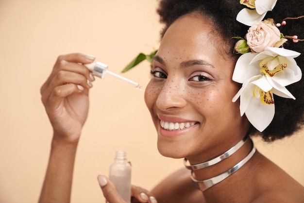 Retrato, de, joven, pecoso, mujer afroamericana, tenencia, facial, suero, crema, botella