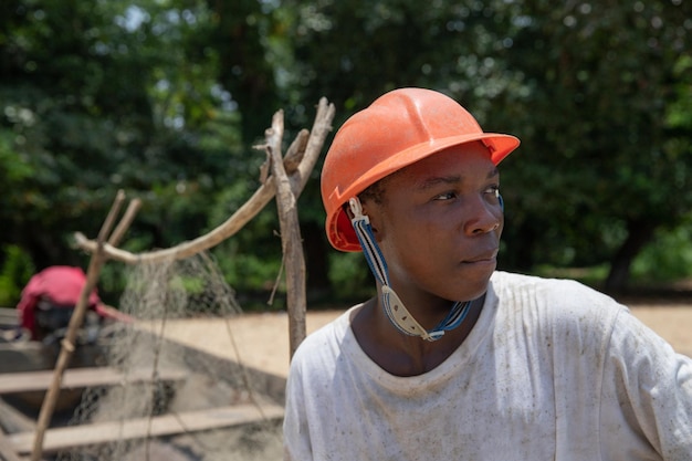 Foto retrato de un joven pescador africano con casco protector y mirando a su alrededor