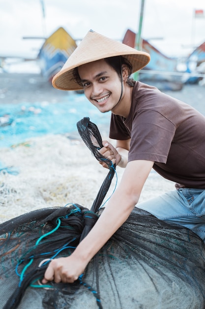 Retrato de un joven pescador preparando una red de pesca