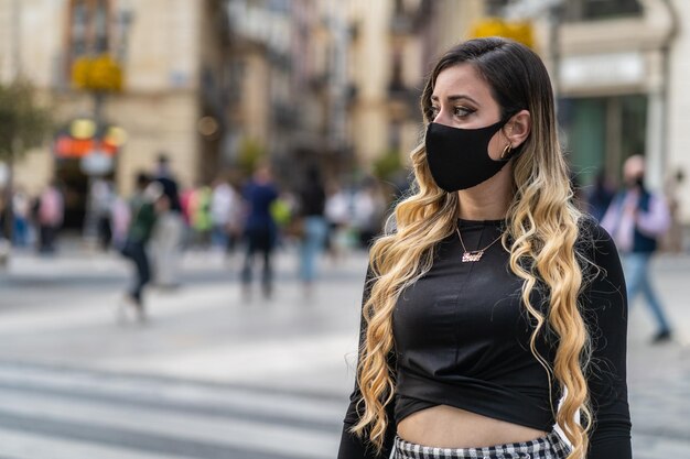 Retrato de una joven de pie en la calle de la ciudad durante la covid-19