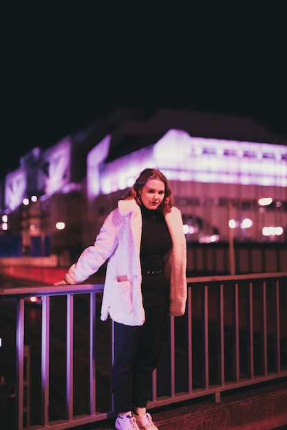 Retrato de una joven de pie en la ciudad durante el invierno por la noche