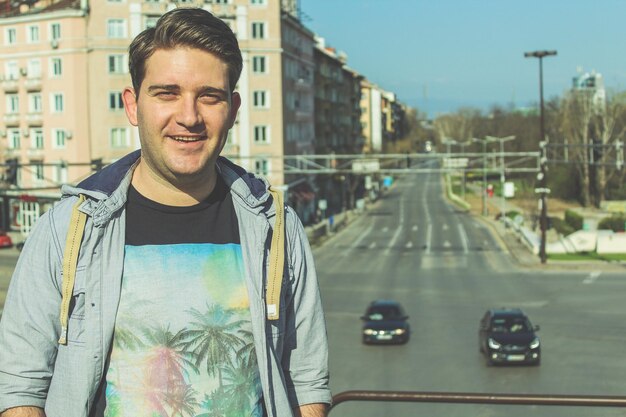 Foto retrato de un joven de pie en la ciudad