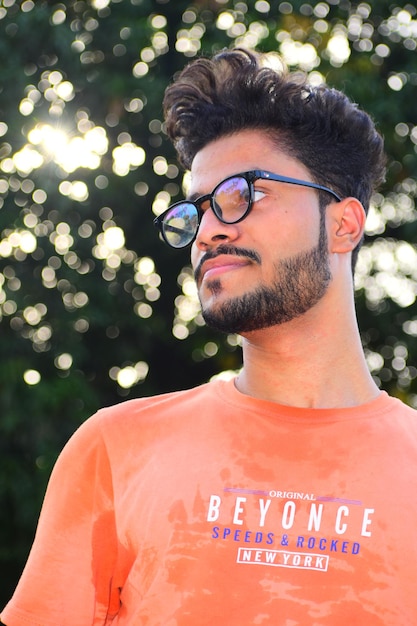 Retrato de un joven de pie contra un árbol