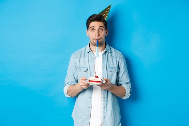 Foto retrato de un joven de pie contra un fondo azul