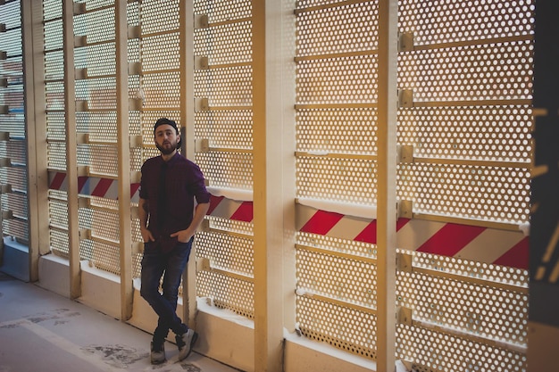 Retrato de un joven de pie junto a una pared de metal