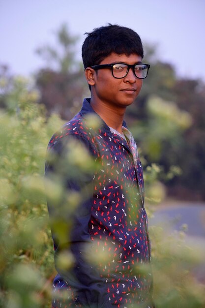 Foto retrato de un joven de pie junto a las plantas