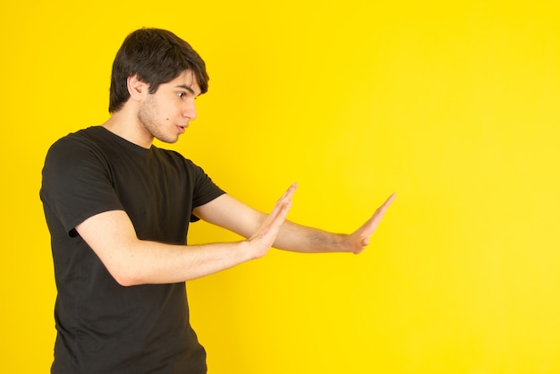 Retrato de un joven de pie y posando contra el amarillo.