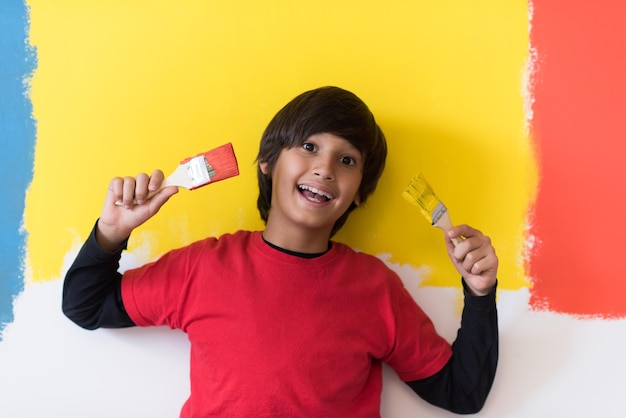 Retrato de un joven pintor con pinceles en las manos frente a un fondo de color