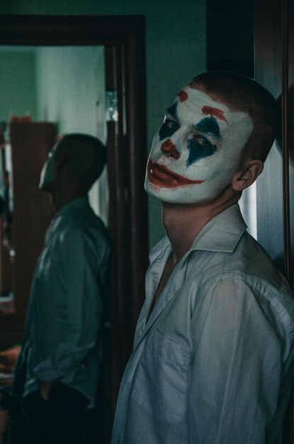 Retrato de un joven con pintura facial de pie contra la pared