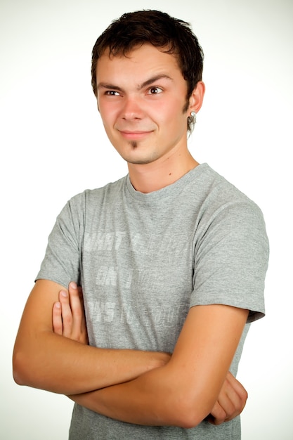 Retrato de un joven positivo caucásico en una camisa gris y jeans posando sobre un fondo gris. Concepto de un joven estudiante exitoso o un empleado novato. Espacio publicitario