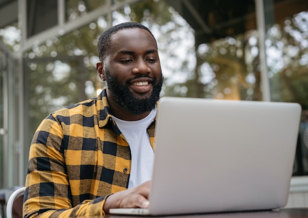 Retrato de joven programador afroamericano con ordenador portátil