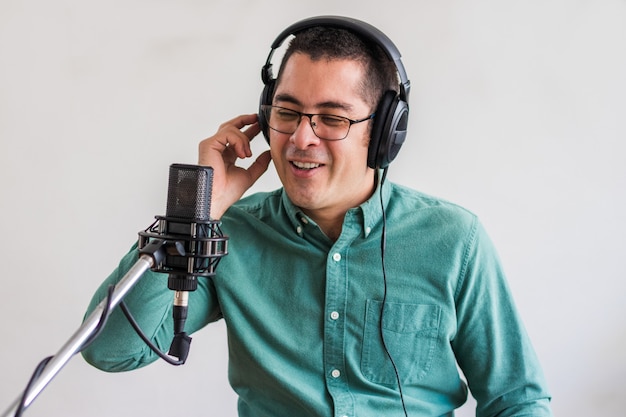 Retrato de un joven que ejecuta un podcast en vivo desde su casa y él está sentado a la mesa con un portátil