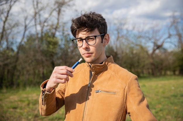 Retrato de un joven que fuma un cigarrillo electrónico.