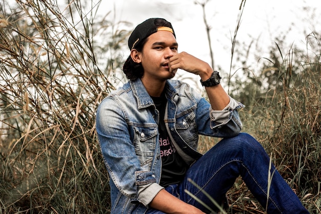 Foto retrato de un joven que mira hacia otro lado mientras está sentado en el campo