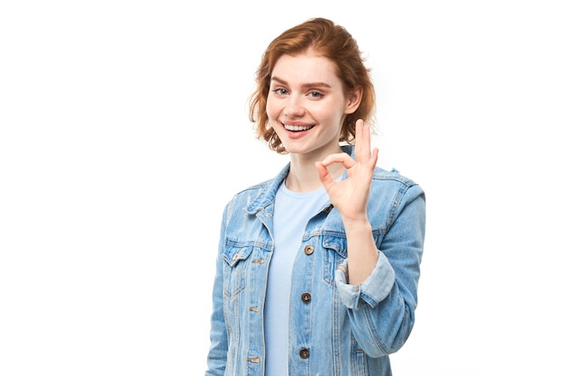 Retrato de una joven que muestra el signo OK con los dedos aislado sobre fondo blanco Concepto aceptado de carrera exitosa