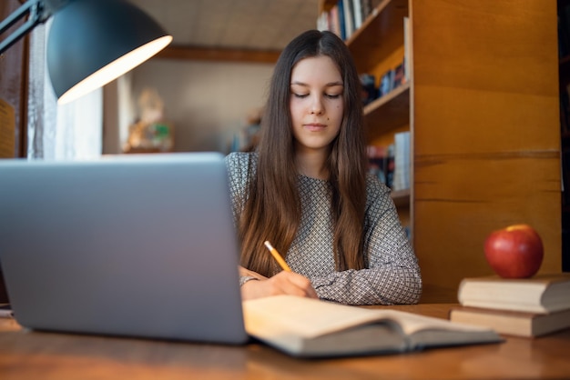 Retrato de una joven que trabaja en la biblioteca universitaria preparándose para las próximas clases leyendo literatura Estudiante femenina estudiando en la biblioteca