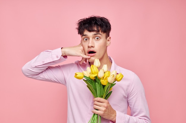 Retrato de un joven ramo de flores amarillas romance posando moda fondo rosa inalterado