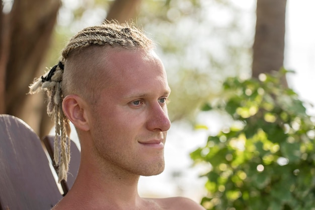 Retrato de un joven con rastas en la cabeza en la naturaleza Cerrar