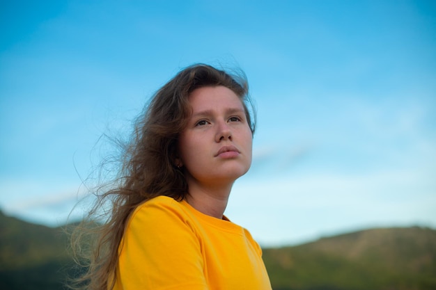 Retrato de una joven relajada, triste y pensativa, de pie al aire libre en el cielo natural y