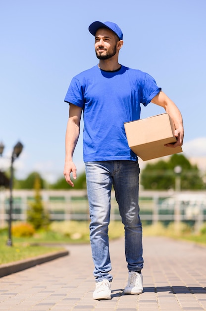 Retrato de joven repartidor llevando caja