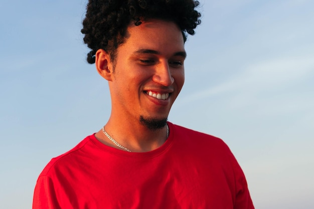 Retrato de un joven riendo con pelo rizado al aire libre