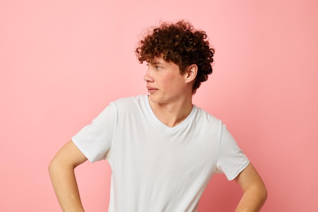 Retrato de un joven rizado en camiseta blanca ropa casual emociones fondo rosa inalterado