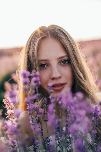 Retrato de una joven rubia en un campo de lavanda en verano al atardecer