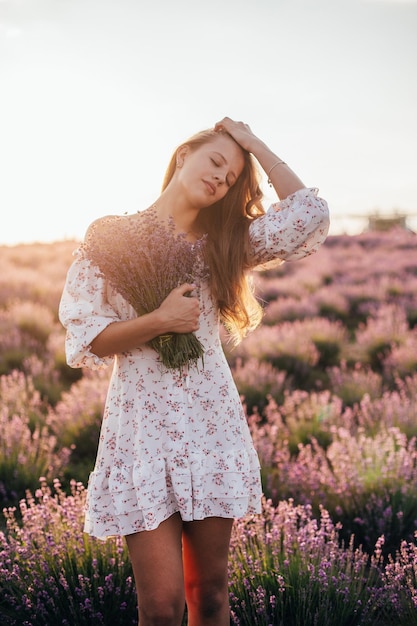 Retrato de una joven rubia en un campo de lavanda en verano al atardecer