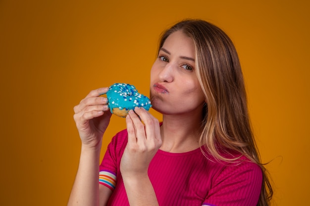 Retrato de una joven rubia comiendo unas deliciosas donas de colores.