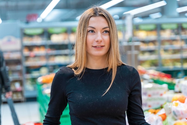 Retrato de una joven rubia haciendo compras en el departamento de frutas del supermercado