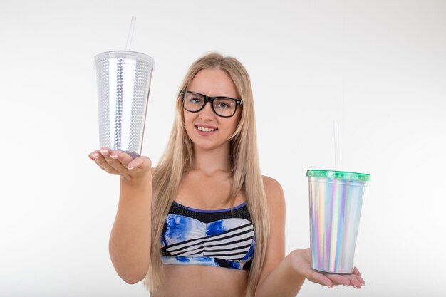 Retrato de una joven rubia en traje de baño azul sosteniendo dos vasos de limonada