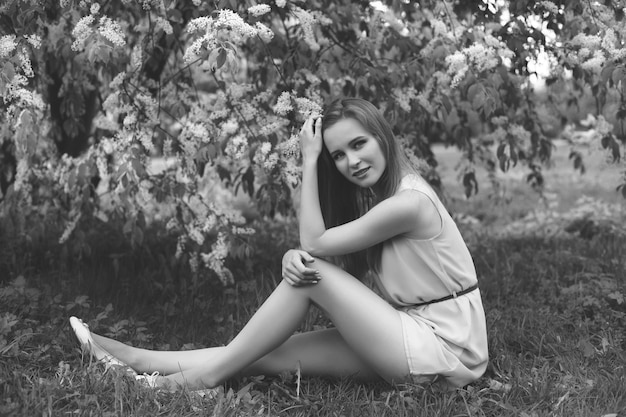 Retrato de una joven rubia con un vestido azul. árboles en flores.