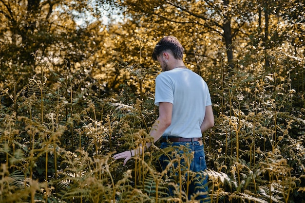 Retrato de un joven rubio que huele algunas hojas verdes en un parque en primavera. Aventura