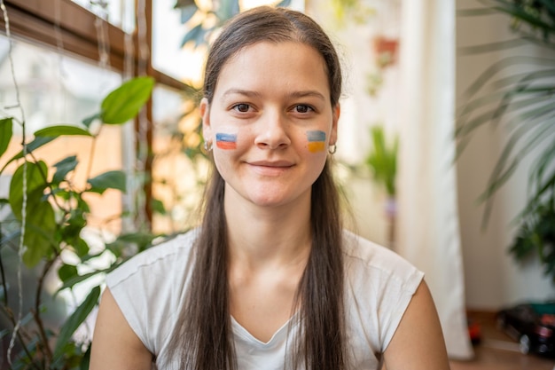 Retrato de una joven rusa ucraniana con la bandera de Ucrania y Rusia en la cara El concepto de participación del pueblo ucraniano en la guerra con Rusia No es un concepto de guerra