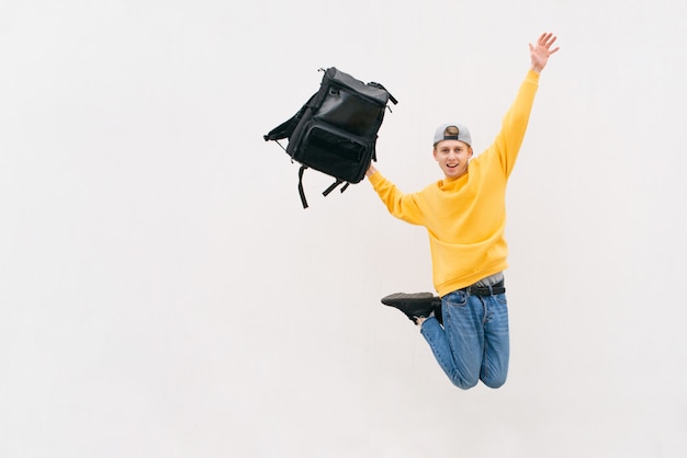 Foto retrato de un joven saltando con una mochila