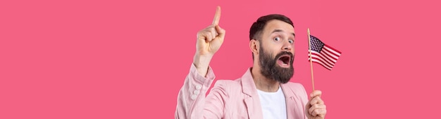 Retrato de un joven satisfecho con barba con una bandera estadounidense sobre un fondo de estudio rojo Gran patriota estadounidense y defensor de la libertad