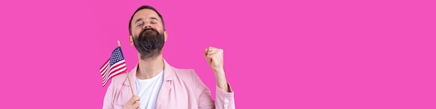 Retrato de un joven satisfecho con barba con una bandera estadounidense sobre un fondo de estudio rojo Gran patriota estadounidense y defensor de la libertad