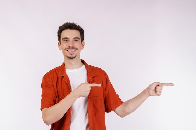 Retrato de joven señalando con el dedo el espacio de copia aislado sobre fondo blanco de estudio