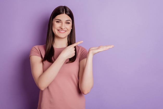 Retrato de joven señalando el producto con el dedo oferta promocional ad aconsejar elegir seleccionar aislado sobre fondo de color violeta