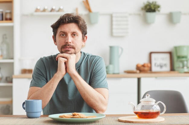 Retrato de joven sentado a la mesa durante su desayuno en casa