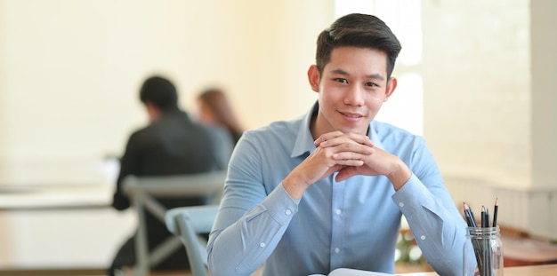 Retrato de un joven sentado en una mesa