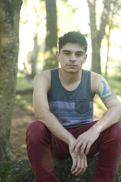 Retrato de un joven sentado en una roca en el bosque